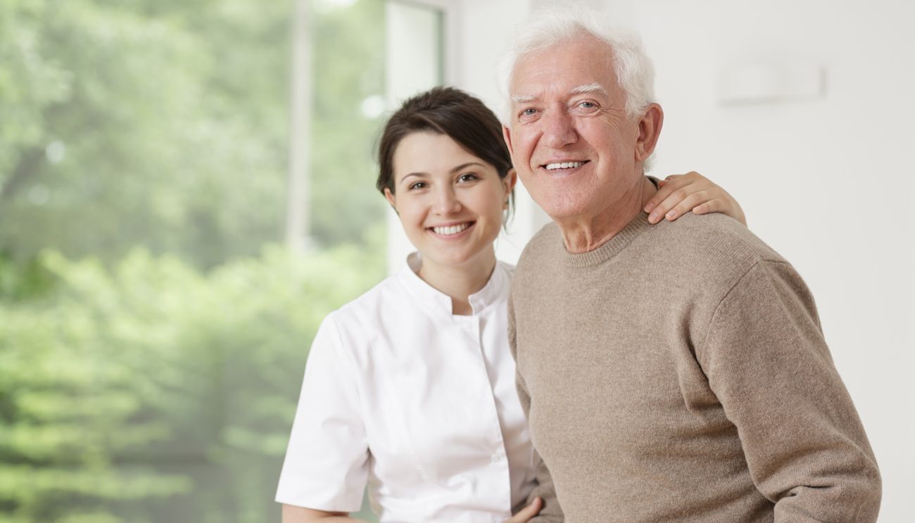 Junge Altenpflegerin umarmt älteren Mann